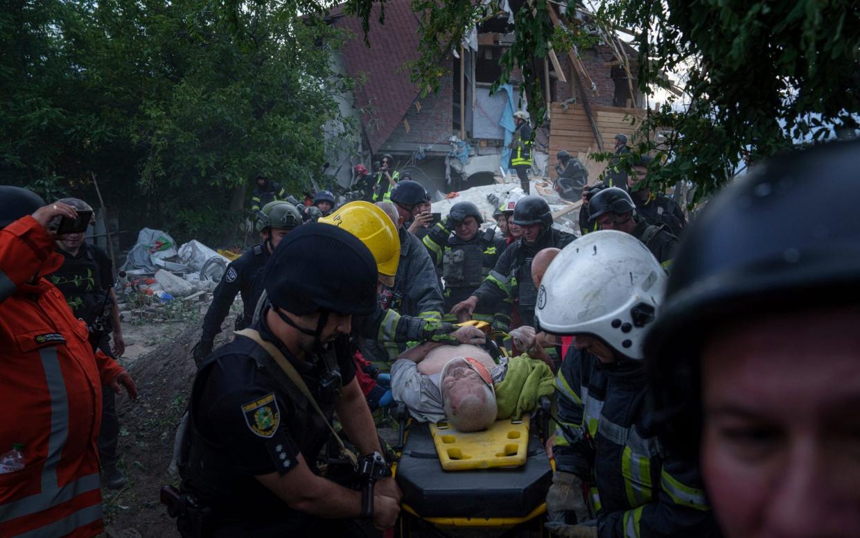 Rescue workers carry an injured person from a building destroyed bya Russian airstrike in Kharkiv