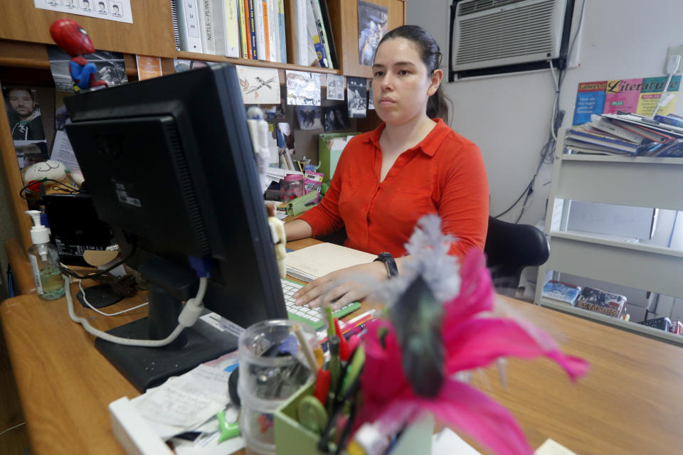 Library Director Jennifer Ramirez works to get her computer operational with assistance from their technology advisers at the public library in Wilmer, Texas, Thursday, Aug. 22, 2019. Cyberattacks that recently crippled nearly two dozen Texas cities, including Wilmer, have put other local governments on guard. Ramirez said that currently only one computer is operational at the library. (AP Photo/Tony Gutierrez)