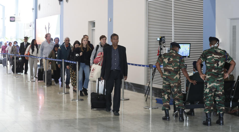 Sri Lankan health officials and military personnel monitor passengers through a thermal scanner at the Katunayake International airport in Colombo, Sri Lanka, Thursday, Jan. 30, 2020. China counted 170 deaths from a new virus Thursday and more countries reported infections, including some spread locally, as foreign evacuees from China's worst-hit region returned home to medical observation and even isolation. (AP Photo/Eranga Jayawardena)