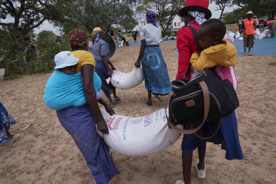 2024年3月22日，辛巴威西南部曼圭區（Mangwe），婦女們背著孩子去領世界糧食計畫署每月配給下來的穀物。美聯社