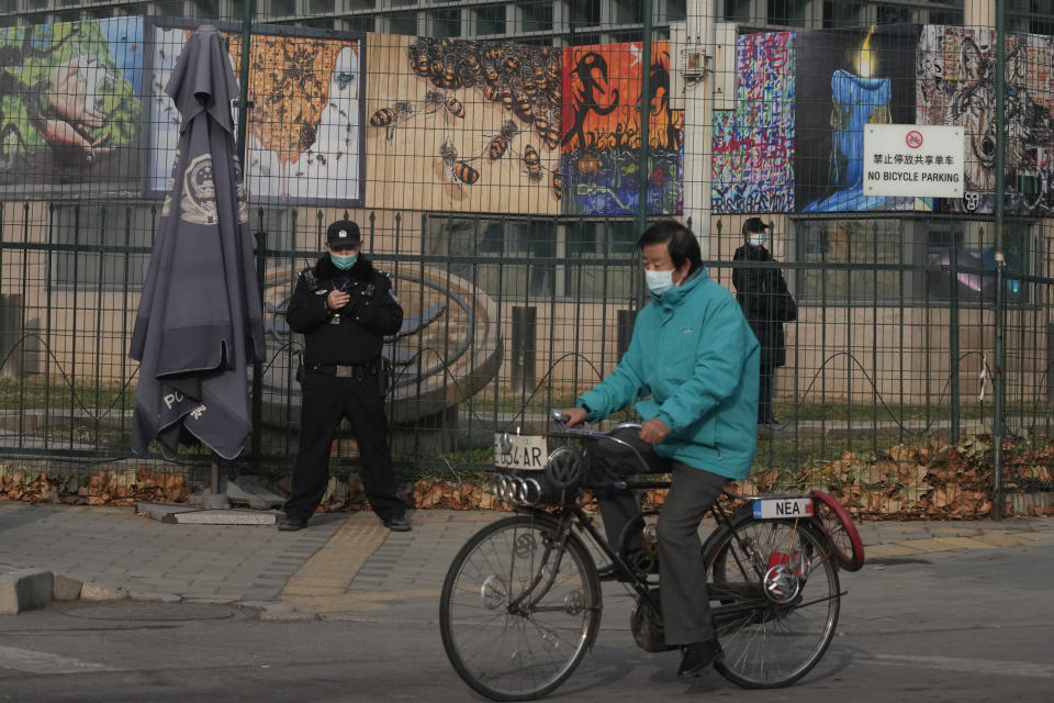 A resident on bicycle past by security personnel outside the U.S. Embassy in Beijing, China, Tuesday, Nov. 16, 2021. U.S. President Joe Biden opened his virtual meeting with China's President Xi Jinping by saying the goal of the two world leaders should be to ensure that competition between the two superpowers "does not veer into conflict." (AP Photo/Ng Han Guan)