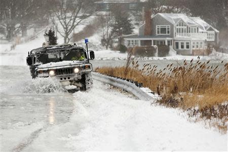 A police vehicle drives through a flooded street during a winter nor'easter snow storm in Scituate