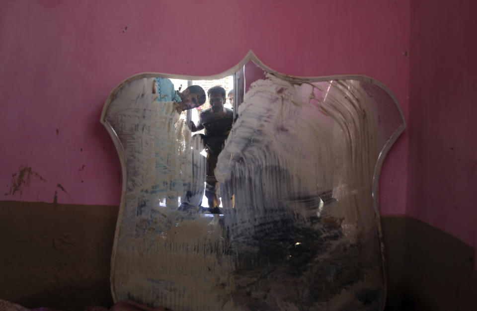 Afghans are reflected in a mirror in their house that was damaged by a mudslide, in Parwan province, north of Kabul, Afghanistan, Thursday, Aug. 27, 2020. The death toll from heavy flooding in northern and eastern Afghanistan rose to at least 150 on Thursday, with scores more injured as rescue crews searched for survivors beneath the mud and rubble of collapsed houses, officials said. (AP Photo/Rahmat Gul)