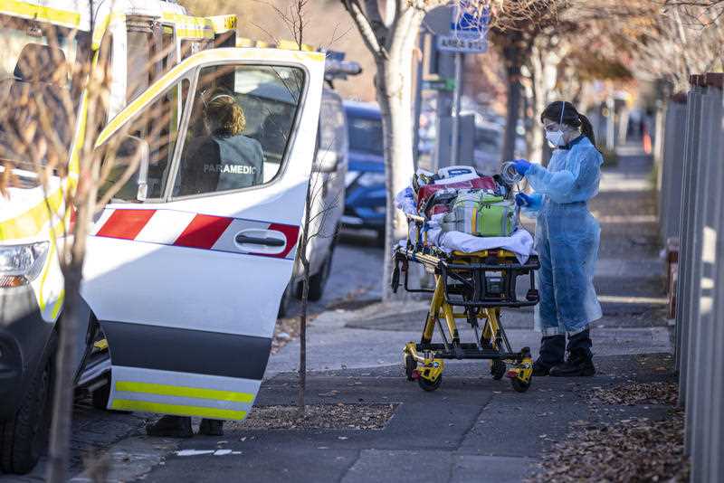 Paramedics return a trolley and equipment to an ambulance outside Royal Freemasons Coppin Centre, Melbourne.