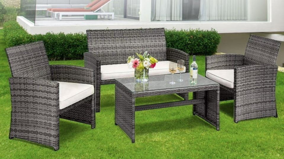 the beige and gray patio set (two chairs, a sofa and table) in a yard