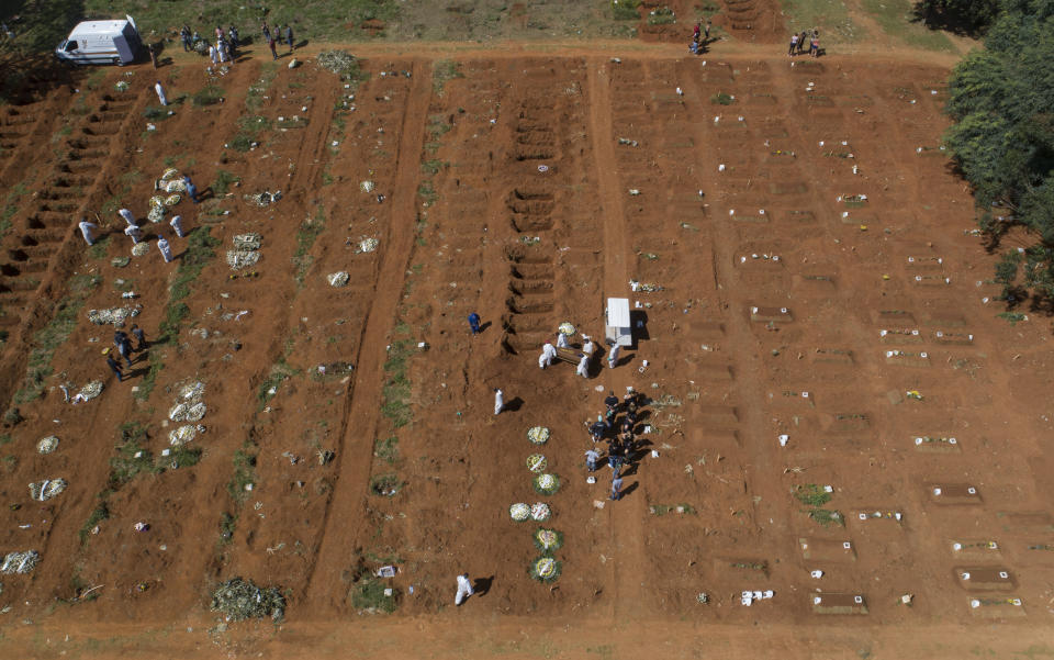 Empleados de cementerio con vestimenta protectora cargan el ataúd con los restos de una persona que murió de complicaciones derivadas del COVID-19 en el cementerio Vila Formosa, Sao Paulo, Brasil, 24 de marzo de 2021. (AP Foto/Andre Penner)