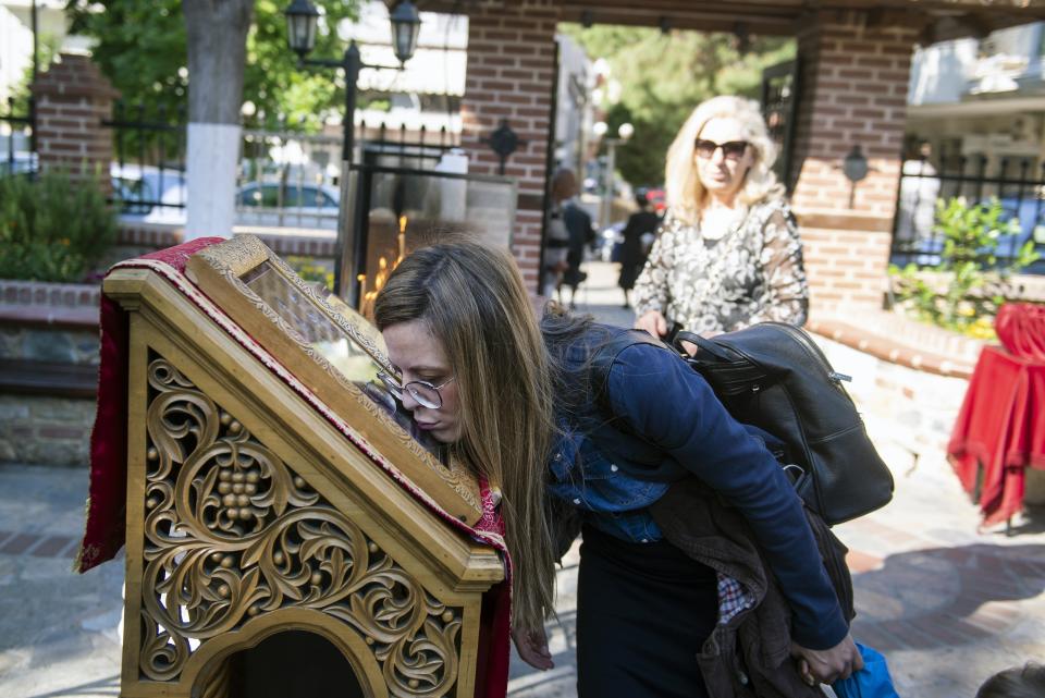 In this Sunday, May 24, 2020, photo, a woman kisses an icon as she attends Sunday Mass outside a Greek Orthodox church in the northern city of Thessaloniki, Greece. Priests at the church still use a traditional shared spoon to distribute Holy Communion. Contrary to science, church officials say it is impossible for any disease, including the coronavirus, to be transmitted through Holy Communion. (AP Photo/Giannis Papanikos)