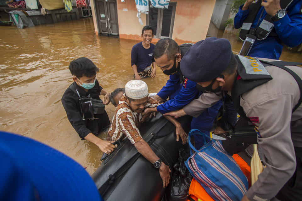 Rescuers assist an elderly man to climb into their boat at a flooded village in Banjar, South Kalimantan on Borneo Island, Indonesia, in this Saturday, Jan. 16, 2021 photo. Many thousands of people have been evacuated and a number have been killed in recent days in flooding on Indonesia's Borneo island, officials said Sunday. (AP Photo/Putra)