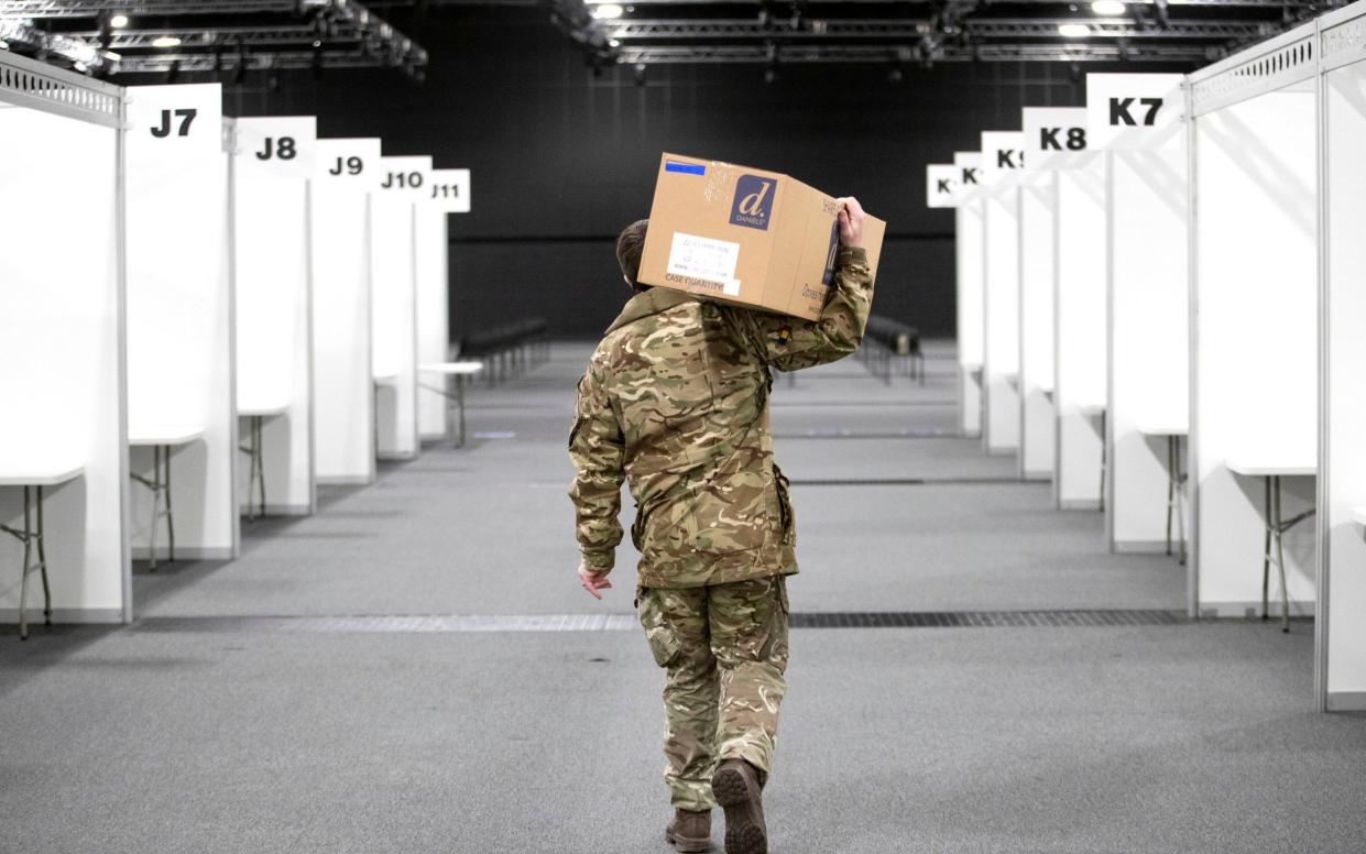 A member of the Royal Scots Dragoon Guard carries in supplies as part of the preparations setting up a mass Covid vaccination centre at the P and J Live Arena in Aberdeen - PA