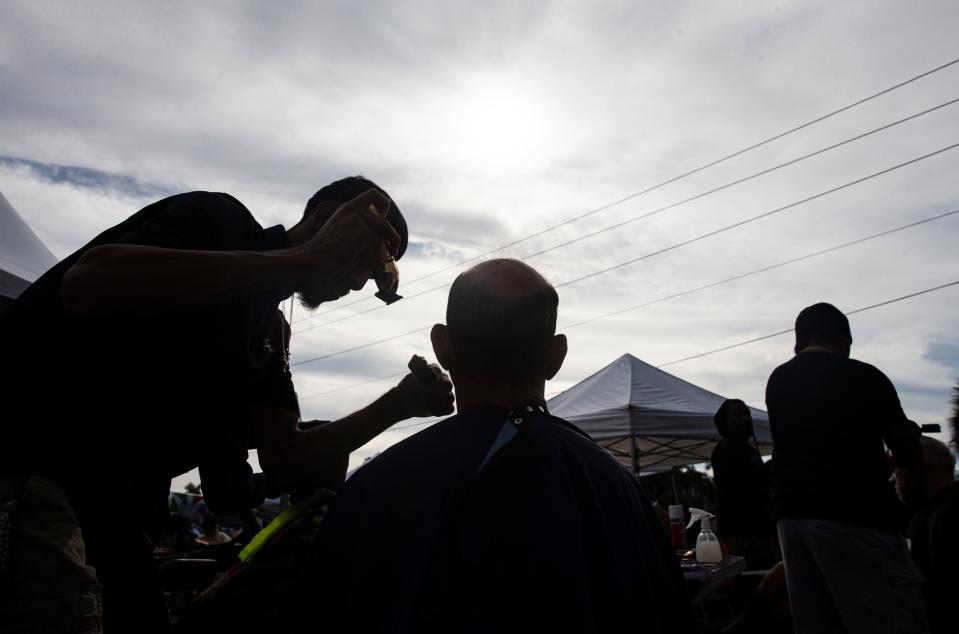 Angel Mijangos, a student at Itech in Immokalee trims John YeomanÕs hair at Collier County Hunger and Homeless CoalitionÕs annual "point in time" homeless count at Gulf Gate Plaza in Naples on Friday, Jan. 26, 2024. Yeoman has been homeless in Naples six years, he said. Vendors were set up at the event to help the homeless which included, food, hygiene kits, clothes and other help.