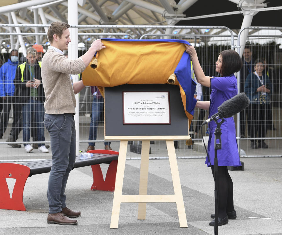 Natalie Grey, head of nursing at NHS Nightingale hospital, right unveils a plaque on behalf of Britain's Prince Charles, during the opening of the NHS Nightingale Hospital at the ExCel centre in London, Friday April 3, 2020. The ExCel centre has been converted into a 4000 bed temporary hospital NHS Nightingale amid the growing coronavirus outbreak. (Stefan Rousseau/Pool Photo via AP)