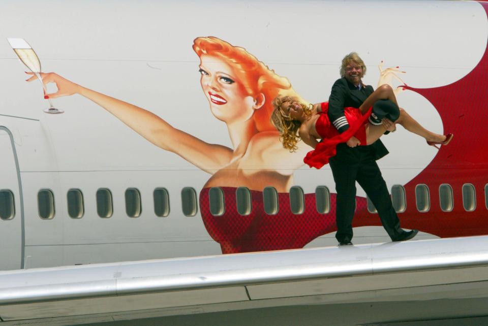 Sir Richard Branson, right, founder and chairman of Virgin Atlantic Airways, carries actress Pamela Anderson off the wing of a limited edition 21st birthday plane with a newly styled 