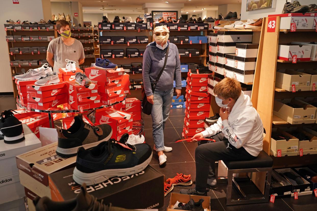 A mother and son wear protective face masks as they shop for shoes at a shoe store that was open for the first time since March on the first day of the easing of some restrictions during the coronavirus crisis on April 20, 2020, in Leipzig, Germany.