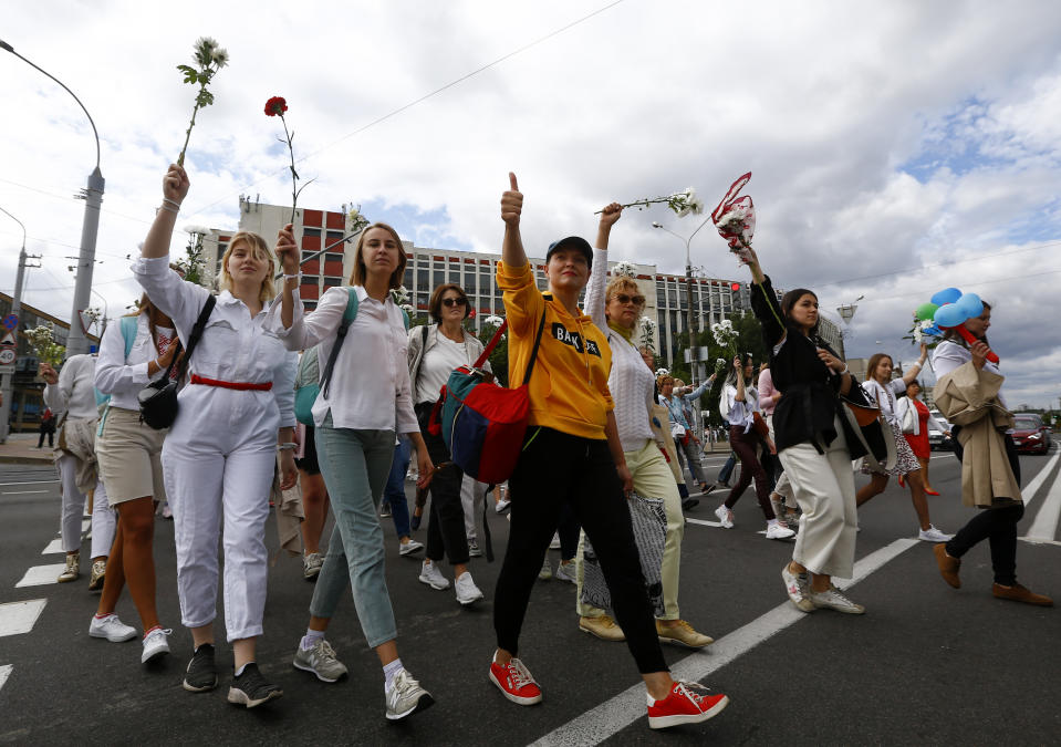 Belarusian women carry flowers on a rally in solidarity with protesters injured in the latest rallies against the results of the country's presidential election in Minsk, Belarus, Thursday, Aug. 13, 2020. Hundreds of people were back on the streets of Belarus' capital on Thursday morning, forming long "lines of solidarity" in protest against an election they say was rigged to extend the rule of the country's authoritarian leader and against a crackdown on rallies that followed the vote. (AP Photo/Sergei Grits)