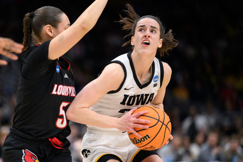 Iowa's Caitlin Clark looks for an open shot as Louisville's Mykasa Robinson defends.