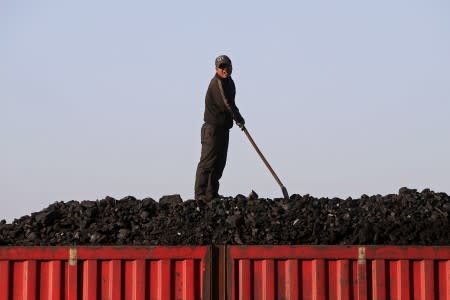 FILE PHOTO: A worker speaks as he loads coal on a truck at a depot near a coal mine from the state-owned Longmay Group on the outskirts of Jixi, Heilongjiang, China
