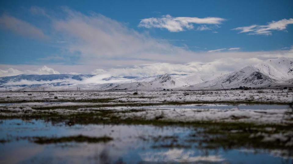 Snow covers the Temblor Range and the California Valley on Feb. 25, 2023, as puddles reflect the blue sky and clouds.