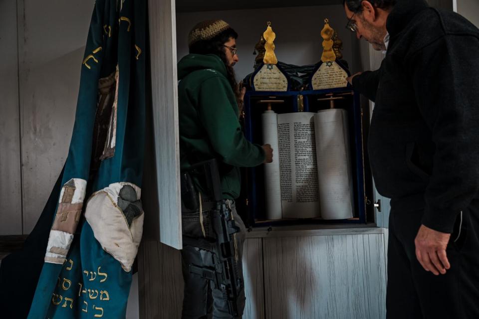 Two men standing, looking at the scrolls of the Torah inside a synagogue