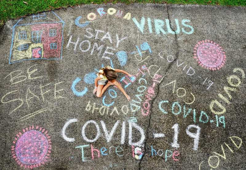 A young girl writes with chalk on her home driveway on the Gold Coast, Tuesday.