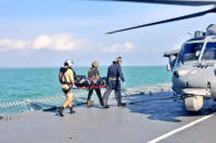 Royal Malaysian Navy personnel carry a body onto a U.S. Navy helicopter from USS America during a search and rescue operation for survivors of the USS John S. McCain ship collision in Malaysian waters August 23, 2017. Royal Malaysian Navy Handout via REUTERS