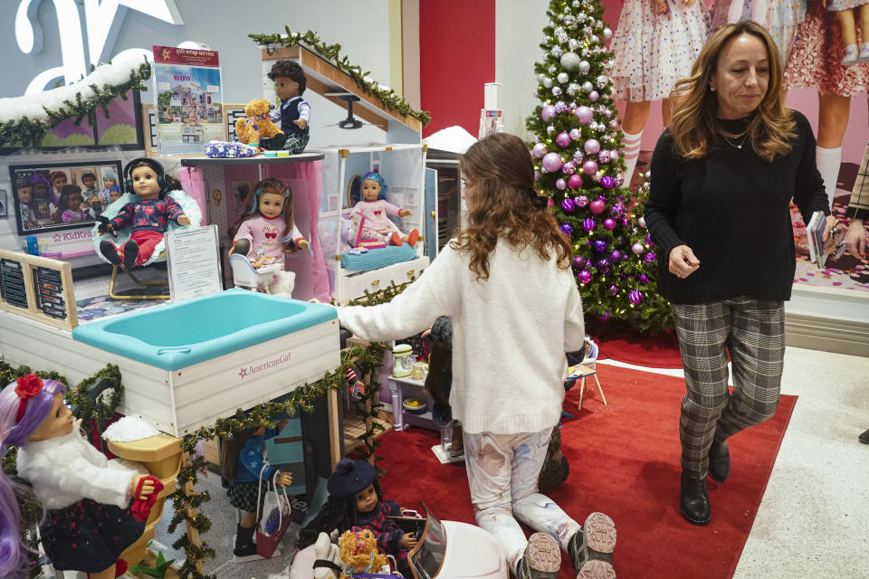 Jamie Cygielman, right, general manager and president at American Girl, leaves a youngster browsing the company's latest holiday showcase doll set, Friday, Dec. 2, 2022, in New York. Cygielman said roughly half its sales went to adults after a relaunch of the first six American Girl dolls in May 2021 to celebrate its 35th anniversary. (AP Photo/Bebeto Matthews)