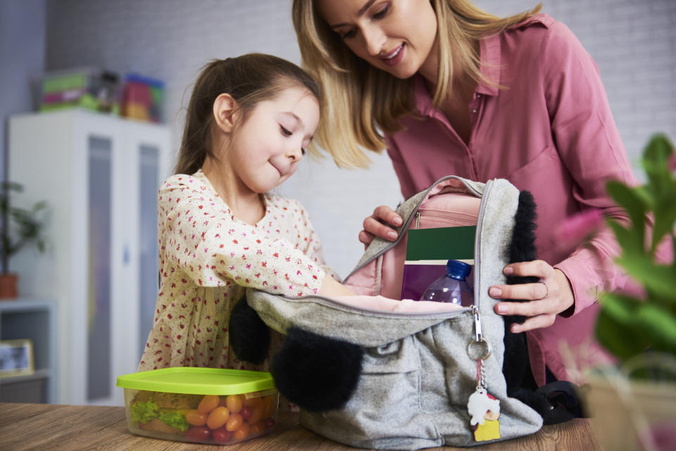 Young mum and daughter packing backpack for the school