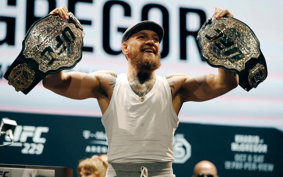 Conor McGregor holds up his belts during a news conference for the UFC 229 fight - AP