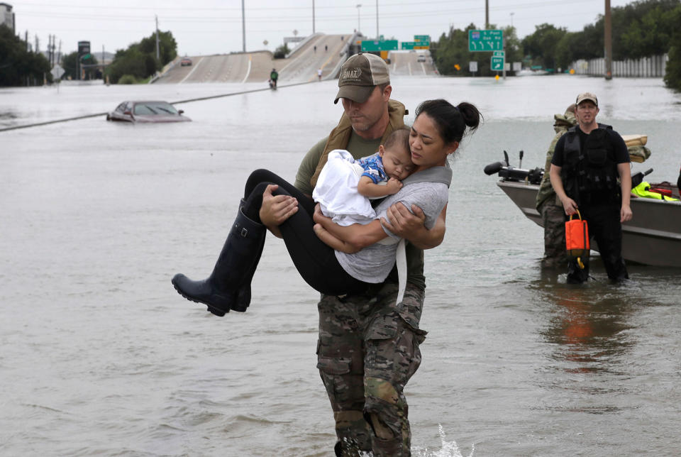 <p>AUG. 27, 2017 – Houston Police SWAT officer Daryl Hudeck carries Catherine Pham and her 13-month-old son Aiden after rescuing them from their home surrounded by floodwaters from Tropical Storm Harvey in Houston. (Photo:David J. Phillip/AP) </p>