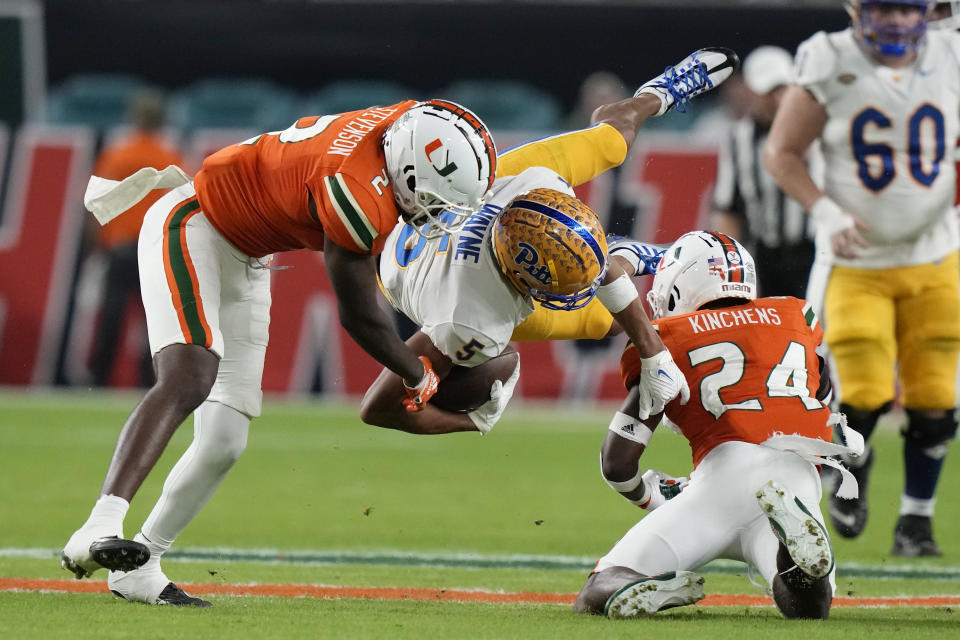 Pittsburgh wide receiver Jared Wayne (5) is tackled by Miami cornerback Tyrique Stevenson (2) and safety Kamren Kinchens (24) during the first half of an NCAA college football game Saturday, Nov. 26, 2022, in Miami Gardens, Fla. (AP Photo/Lynne Sladky)