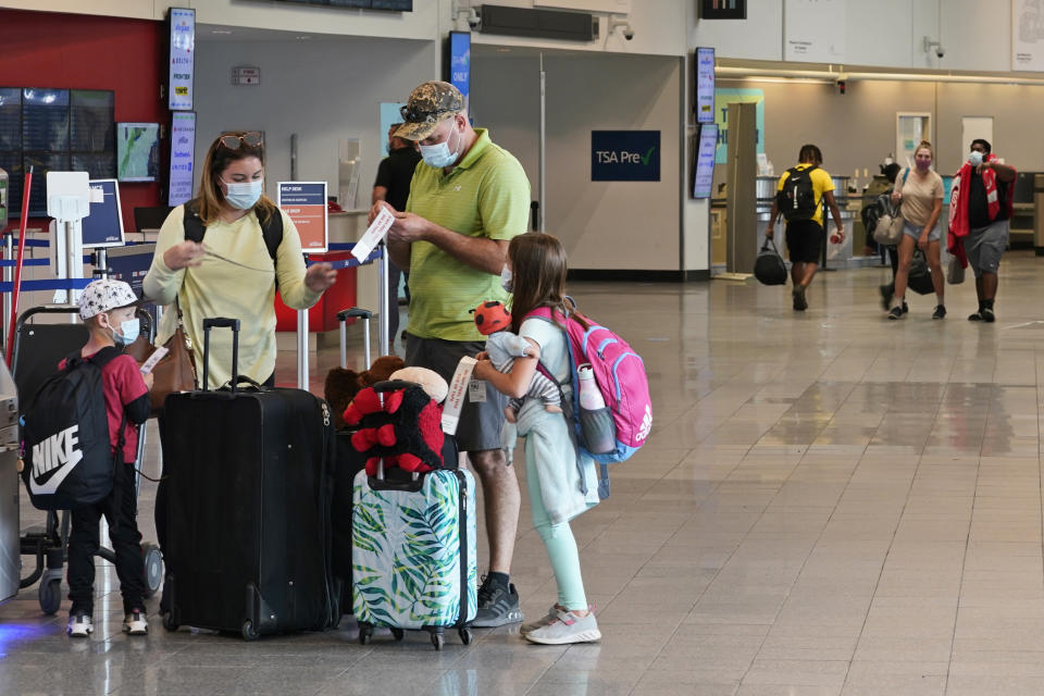 FILE - In this May 26, 2021 file photo, a family gets ready to check-in at Cleveland Hopkins International Airport before flying in Cleveland. Americans were hitting the road in near-record numbers at the start of the holiday weekend. More than 1.8 million people went through U.S. airports on Thursday, and that number could top 2 million over the weekend, the highest mark since early March of last year. (AP Photo/Tony Dejak, File)