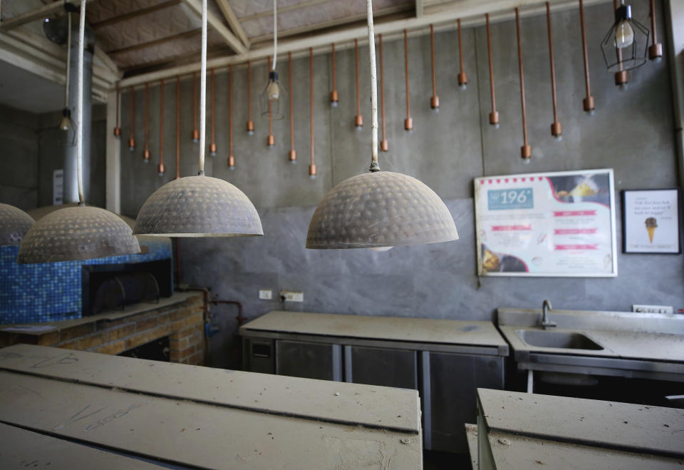 Dust accumulate on lamp shades and serving counters at a closed down ice cream parlor in Bengaluru, India, Thursday, Oct. 15, 2020. Thousands of students and professionals who worked for IT companies and lived in the area have moved back to their native places to work remotely. Even as much of the Indian economy has reopened, Bengaluru’s professional workforce is returning to work at a much slower pace than those in most other major cities, raising the risk that the city faces a more protracted recovery. (AP Photo/Aijaz Rahi)