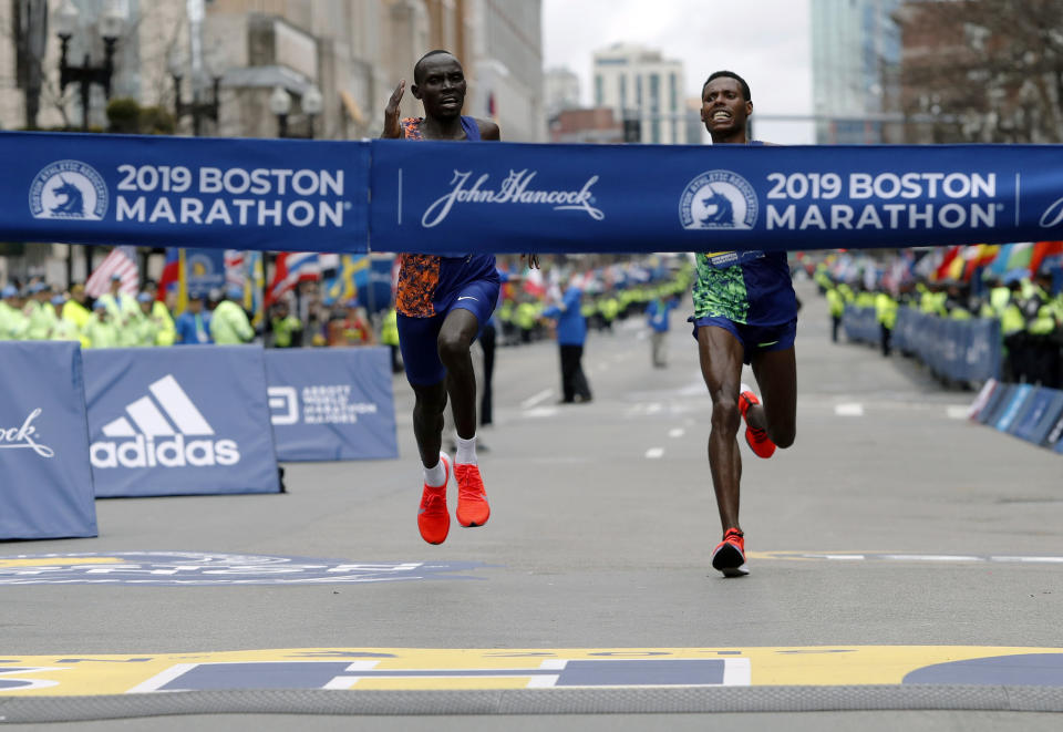 FILE - In this April 15, 2019, file photo, Lawrence Cherono, left, of Kenya, runs to the finish line to win the 123rd Boston Marathon in front of Lelisa Desisa, of Ethiopia, right, in Boston. The Boston Marathon is offering refunds for the first time because of the new coronavirus pandemic. Race organizers say anyone who was entered in the 124th edition of the race this month can still run on the rescheduled date, Sept. 14. But if they can’t make it, they can have their money back. (AP Photo/Winslow Townson, File)