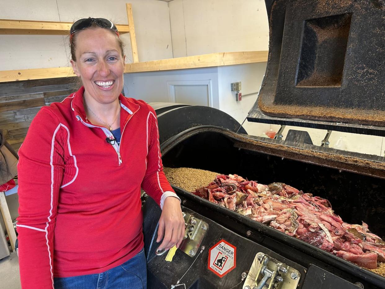 Karine Gignac leans against the in-vessel composter she's using to turn fish waste, spent grains, and wood chips into nutrient-rich compost for Yellowknife gardeners. She plans to start selling it this month. (Liny Lamberink/CBC - image credit)