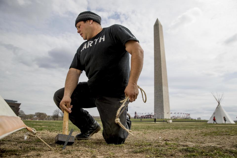 Aldo Seoane of the Yoeme tribe, with a group protesting the Dakota Access oil pipeline, helps set up teepees on the National Mall near the Washington Monument in Washington, Tuesday, March 7, 2017. A federal judge declined to temporarily stop construction of the final section of the disputed Dakota Access oil pipeline, clearing the way for oil to flow as soon as next week. (AP Photo/Andrew Harnik)