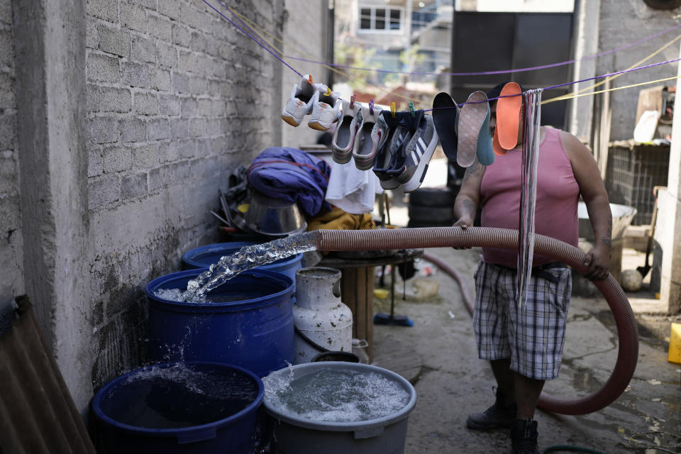 A resident fills industrial pails with water transported by a water truck, in the Iztapalapa neighborhood of Mexico City, Thursday, Feb. 22, 2024. As the election approaches, a worsening water crisis is making it harder for the presidential candidates to ignore Mexico’s climate threats (AP Photo/Eduardo Verdugo)