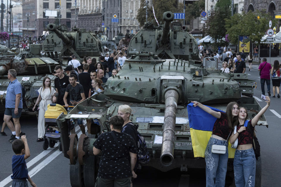 People walk in front of destroyed Russian tanks installed on Khreschatyk street in downtown of Kyiv, Ukraine, Saturday, Aug. 26, 2023. (AP Photo/Evgeniy Maloletka)