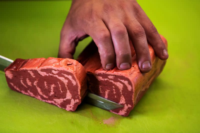 Un chef corta un trozo de bistec vegetal impreso en 3D sin cocinar producido por la empresa israelí Redefine Meat durante una demostración para Reuters en sus instalaciones de Rehovot, Israel