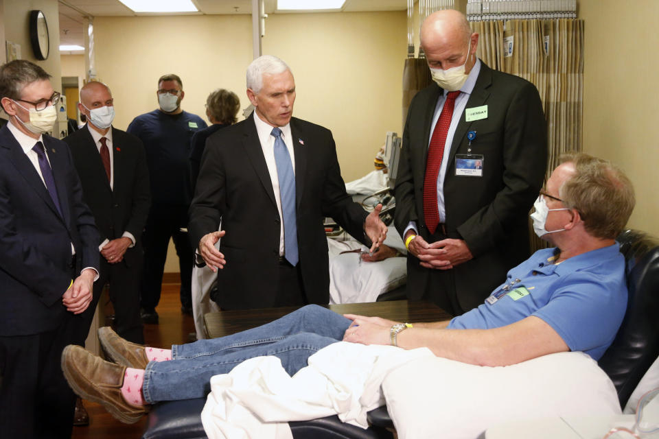 FILE - In this April 28, 2020 file photo, Vice President Mike Pence, center, visits Dennis Nelson, a patient who survived the coronavirus and was going to give blood, during a tour of the Mayo Clinic in Rochester, Minn., as he toured the facilities supporting COVID-19 research and treatment. From the U.S. president to the British prime minister's top aide and far beyond, leading officials around the world are refusing to wear masks or breaking confinement rules meant to protect their populations from the coronavirus and slow the pandemic. While some are punished when they're caught, or publicly repent, others shrug off the violations as if the rules don't apply to them. (AP Photo/Jim Mone, File)