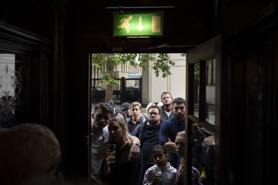 People gather outside a pub to watch a broadcast of Britain's King Charles III first address to the nation following the death of Queen Elizabeth II in London, Friday, Sept. 9, 2022. Queen Elizabeth II, Britain's longest-reigning monarch and a rock of stability across much of a turbulent century, died Thursday Sept. 8, 2022, after 70 years on the throne. She was 96. (AP Photo/Felipe Dana)