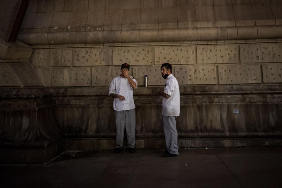 Workers take a cigarette break outside the Bellagio in Las Vegas, Monday, Nov. 9, 2020. To be an immigrant in Las Vegas is to see the coronavirus economy at its worst. Visitors to the area plummeted by more than 90 percent in a little over a month. The state's unemployment rocketed to 28 percent, the worst in the nation and a level not seen even during the Great Depression. (AP Photo/Wong Maye-E)