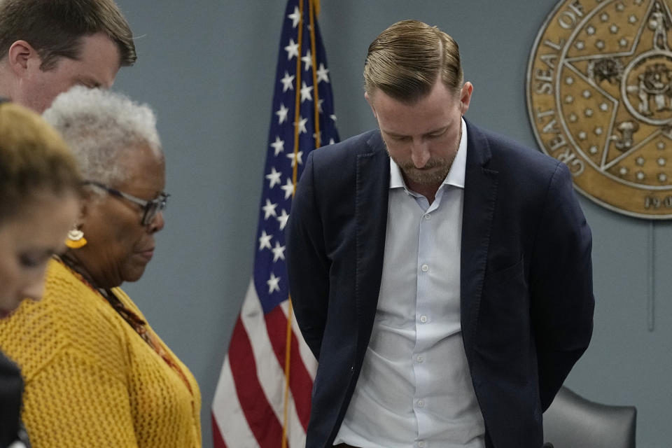 FILE - Superintendent of Public Instruction Ryan Walters, right, bows his head in prayer along with board members during a special state Board of Education meeting to discuss the U.S. Department of Education's "Proposed Change to its Title IX Regulations on Students' Eligibility for Athletic Teams," April 12, 2023, in Oklahoma City. When Walters campaigned for the job last fall, he ran on a platform of fighting "woke ideology" in public schools, banning certain books from school libraries, empowering parents with school choice and getting rid of "radical leftists" he claims were indoctrinating children in classrooms across the state. (AP Photo/Sue Ogrocki, File)