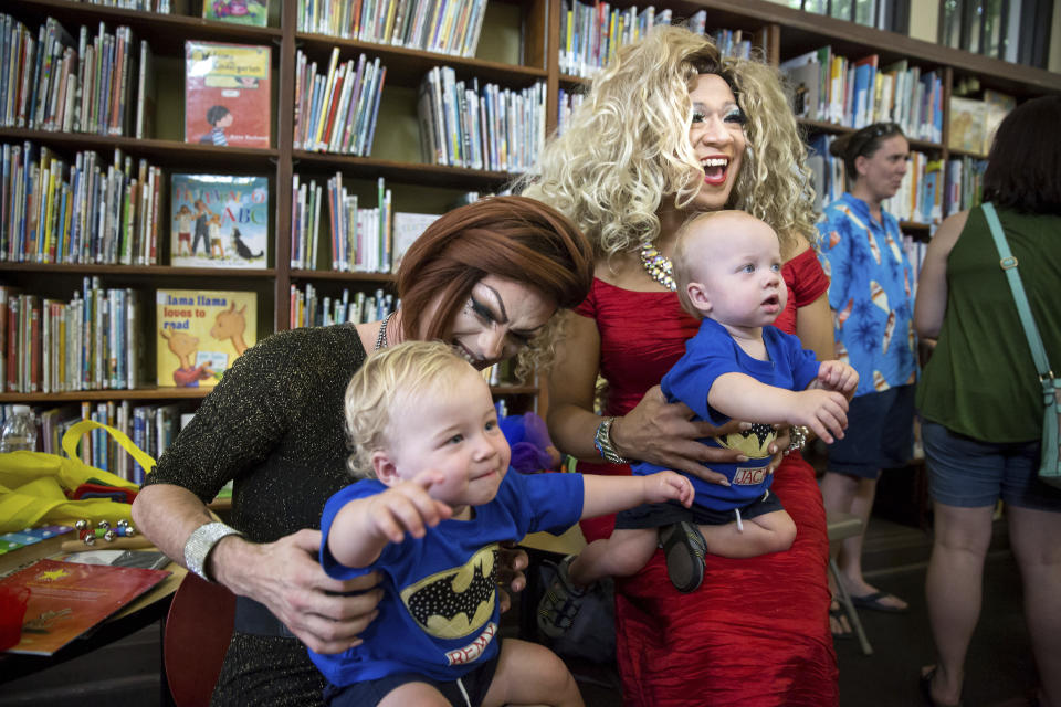 Blazen Haven, left, and Vanessa Carr meet twins Remy Karas, left, and Jack Karas, both 14 months, during Drag Queen Story Time at the Alvar Library in New Orleans on Saturday, Aug. 25, 2018. Children and parents and caregivers packed into the library to hear stories and sing songs during the event. (Scott Threlkeld/The Advocate via AP)