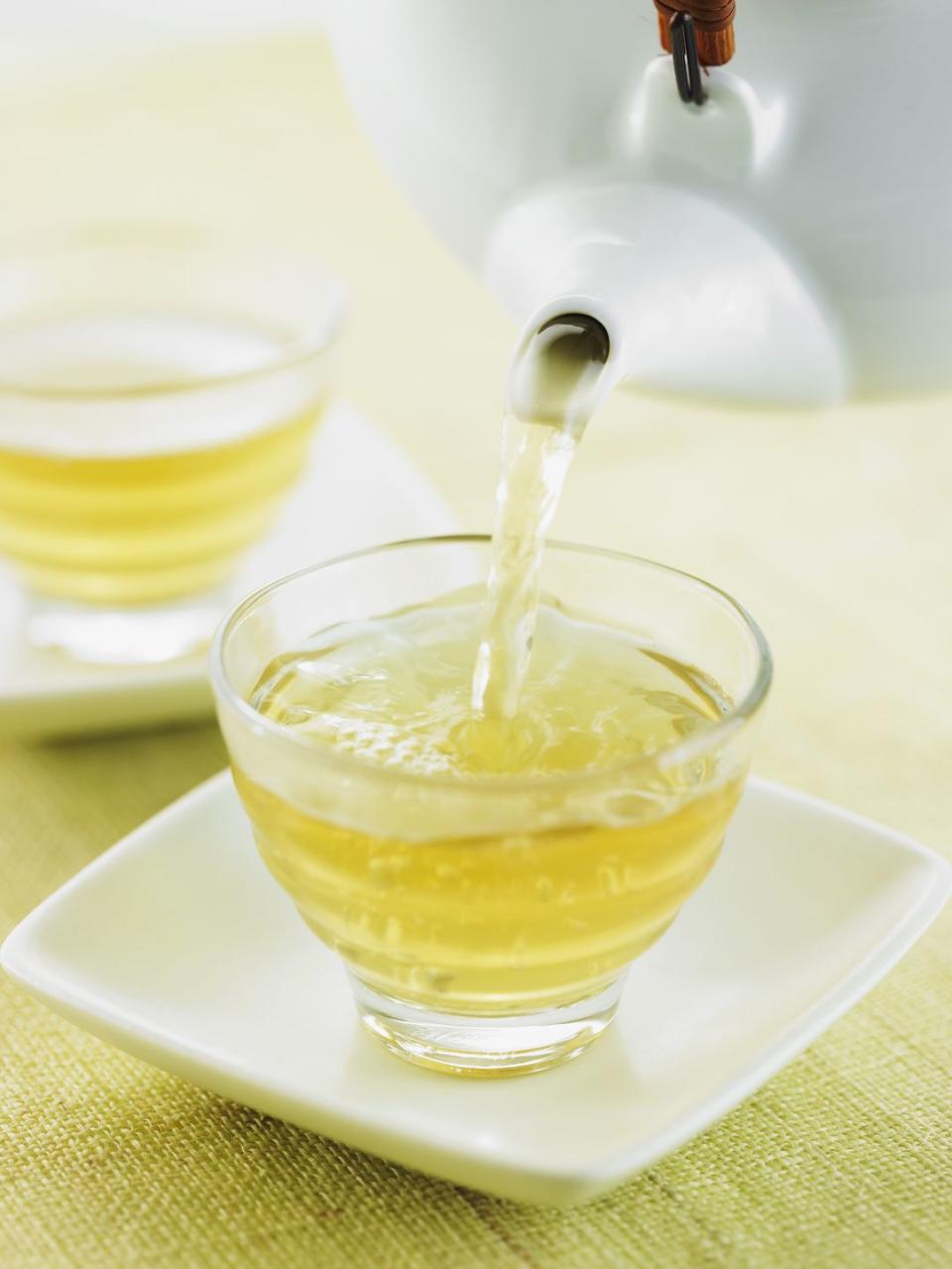 white teapot pouring white tea into a clear glass