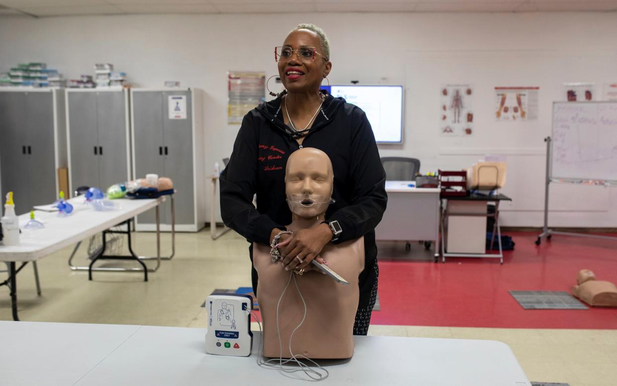 Lei Sean Curtis, 55, smiles as she holds a manikin during a CPR class inside the Phlebotomy Express Training Centers in Detroit on Tuesday, March 12, 2024. Curtis is a certified CPR trainer.