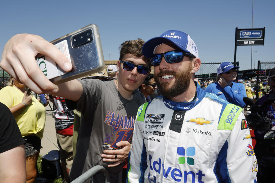 A fan, left, takes a photo with Ross Chastain, right, before a NASCAR Cup Series auto race at Kansas Speedway in Kansas City, Kan., Sunday, May 7, 2023. (AP Photo/Colin E. Braley)