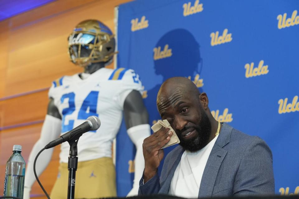 Former UCLA great DeShaun Foster wipes away tears as he's introduced as the school's new football coach on Tuesday.