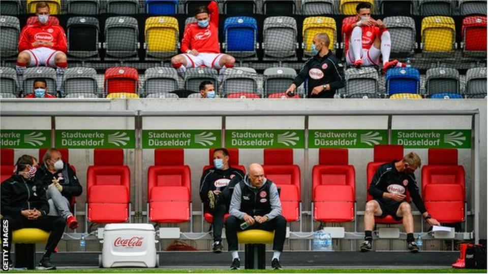 Jugadores con mascaras en un banco de suplentes de Alemania