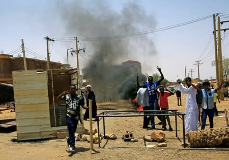 Sudanese protesters gesture and chant slogans at a barricade along a street, demanding that the country's Transitional Military Council hand over power to civilians, in Khartoum