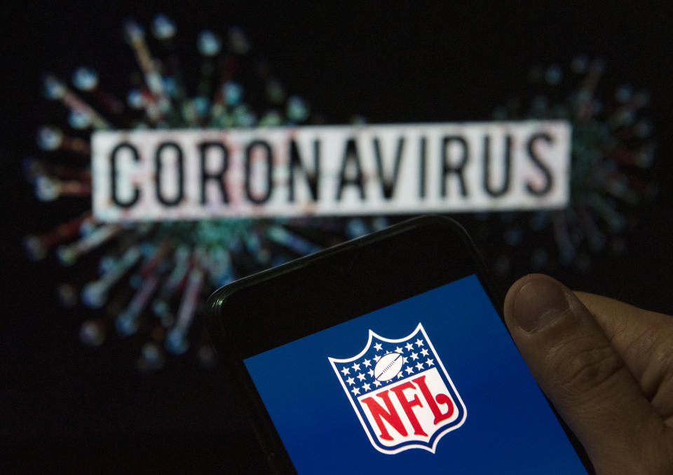 In this photo illustration the American football league The National Football League (NFL)  logo seen displayed on a smartphone with a computer model of the COVID-19 coronavirus on the background. (Photo Illustration by Budrul Chukrut/SOPA Images/LightRocket via Getty Images)