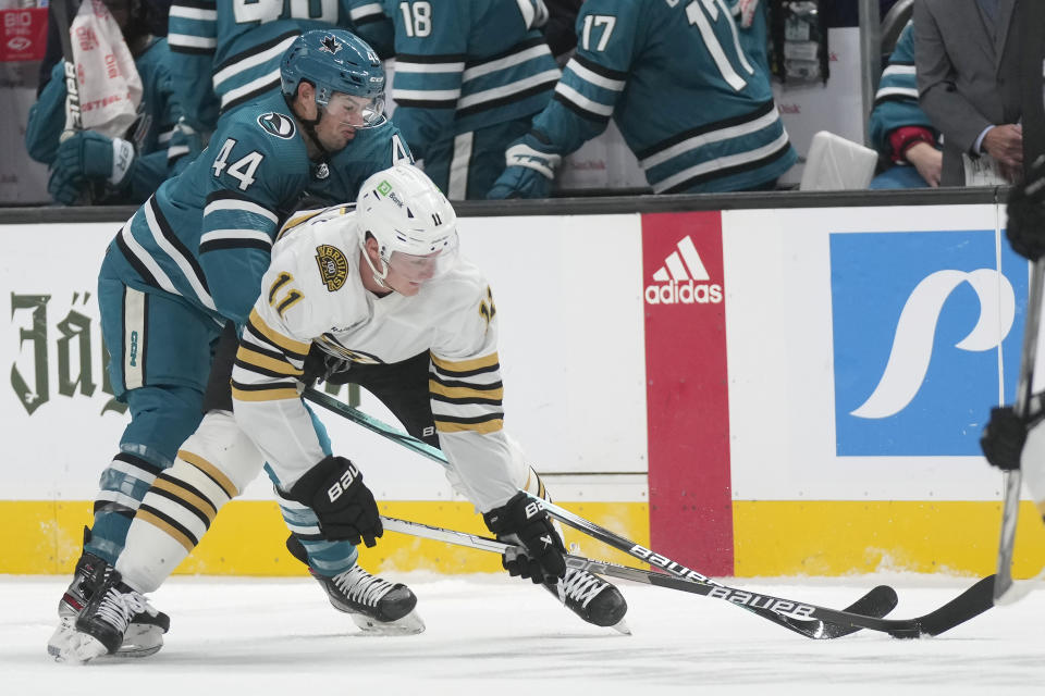 San Jose Sharks defenseman Marc-Edouard Vlasic (44) reaches for the puck from behind Boston Bruins center Trent Frederic (11) during the first period of an NHL hockey game in San Jose, Calif., Thursday, Oct. 19, 2023. (AP Photo/Jeff Chiu)